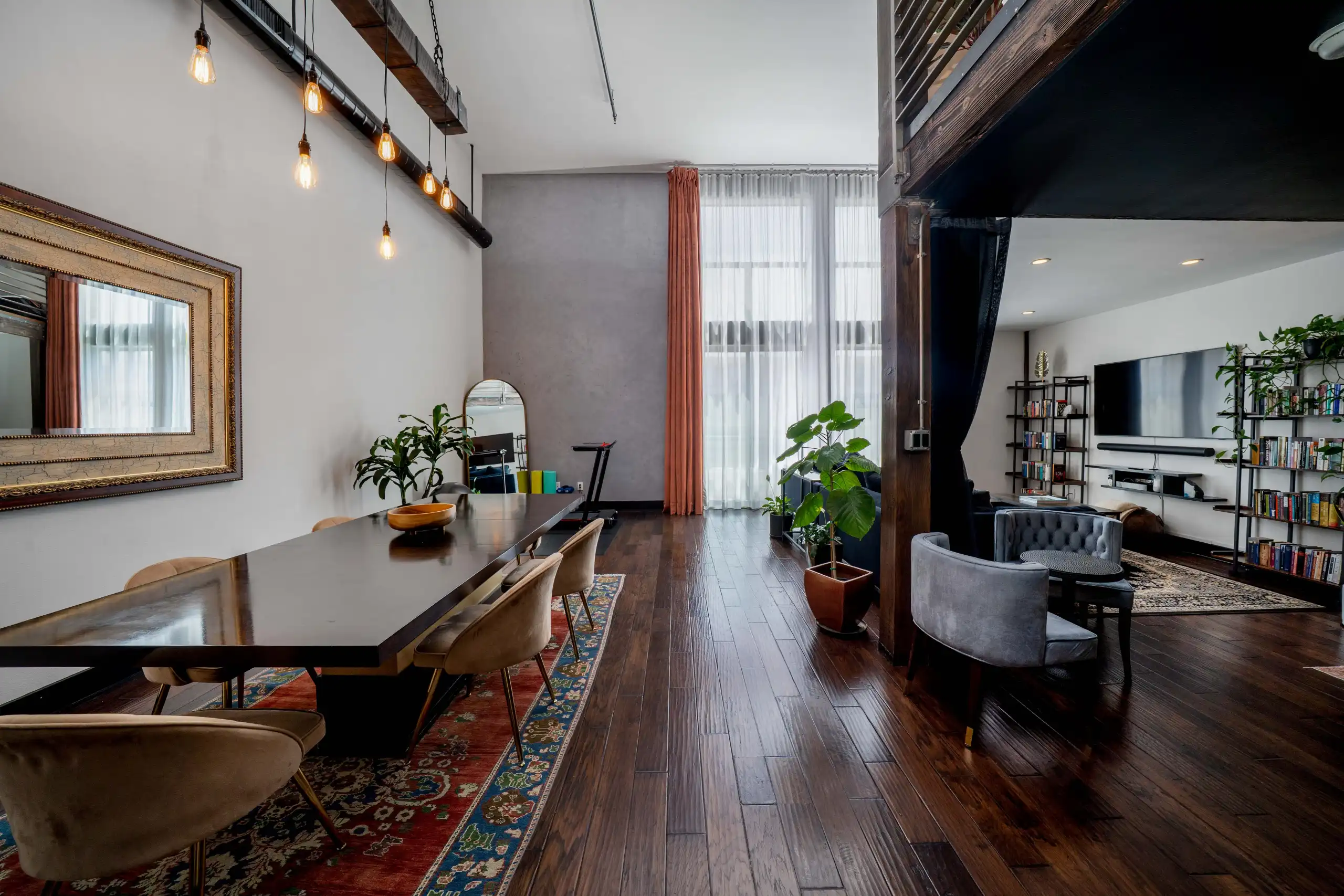 Open concept dining area with long wood table and industrial pendant lighting in Marina Del Rey loft.