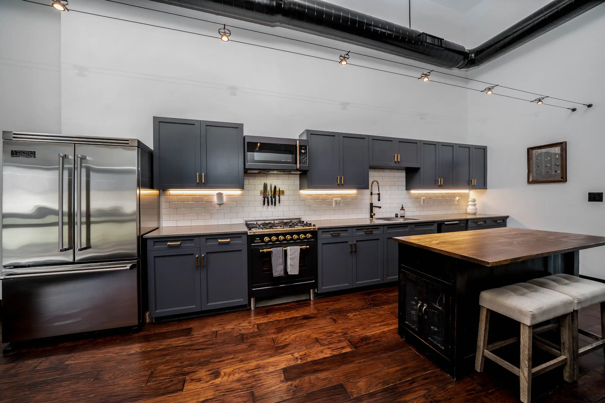 Kitchen with navy blue cabinetry, white subway tile backsplash, and stainless steel appliances in Marina Del Rey.
