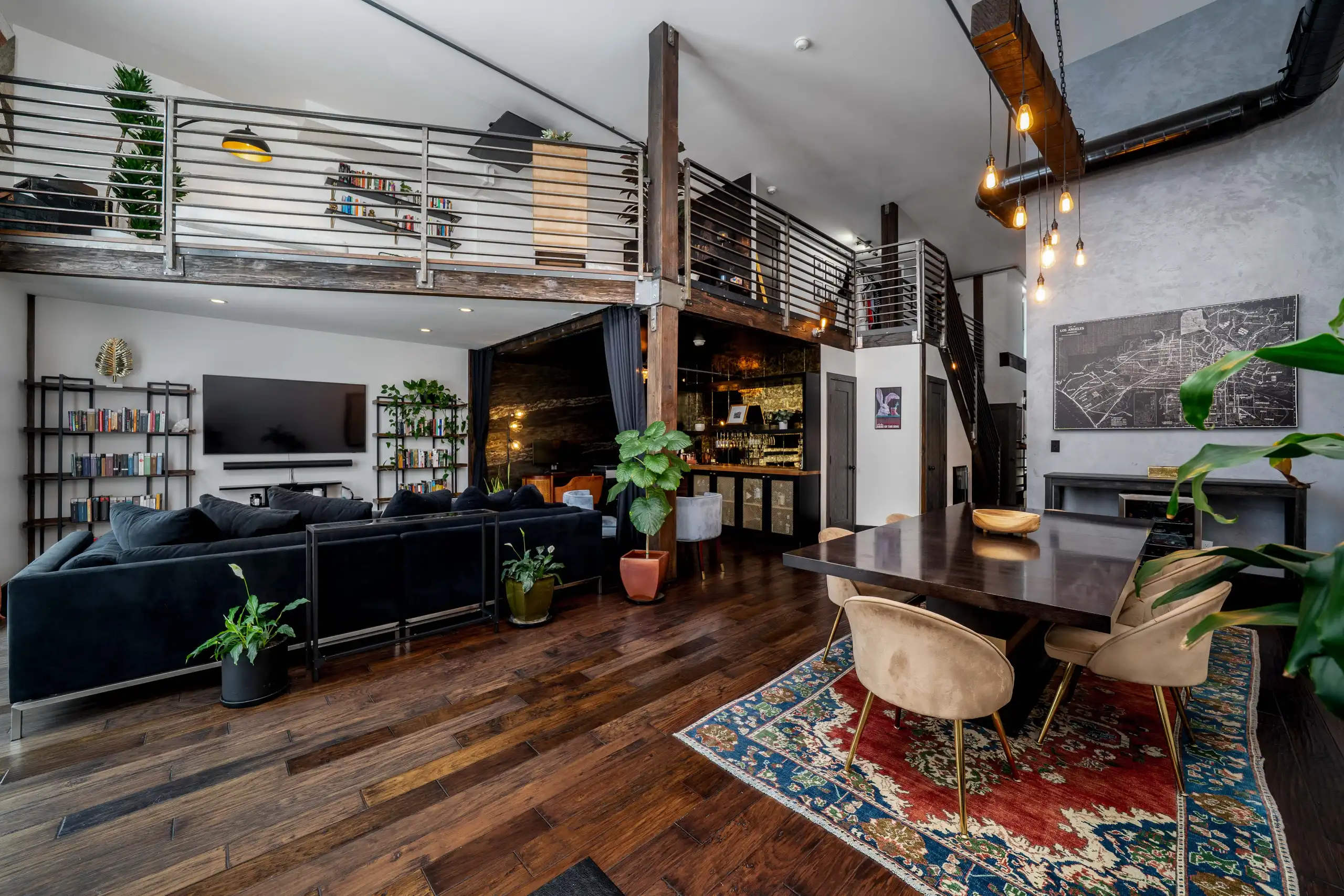 Wide-angle view of an open-concept living and dining area with an upper mezzanine in a loft.