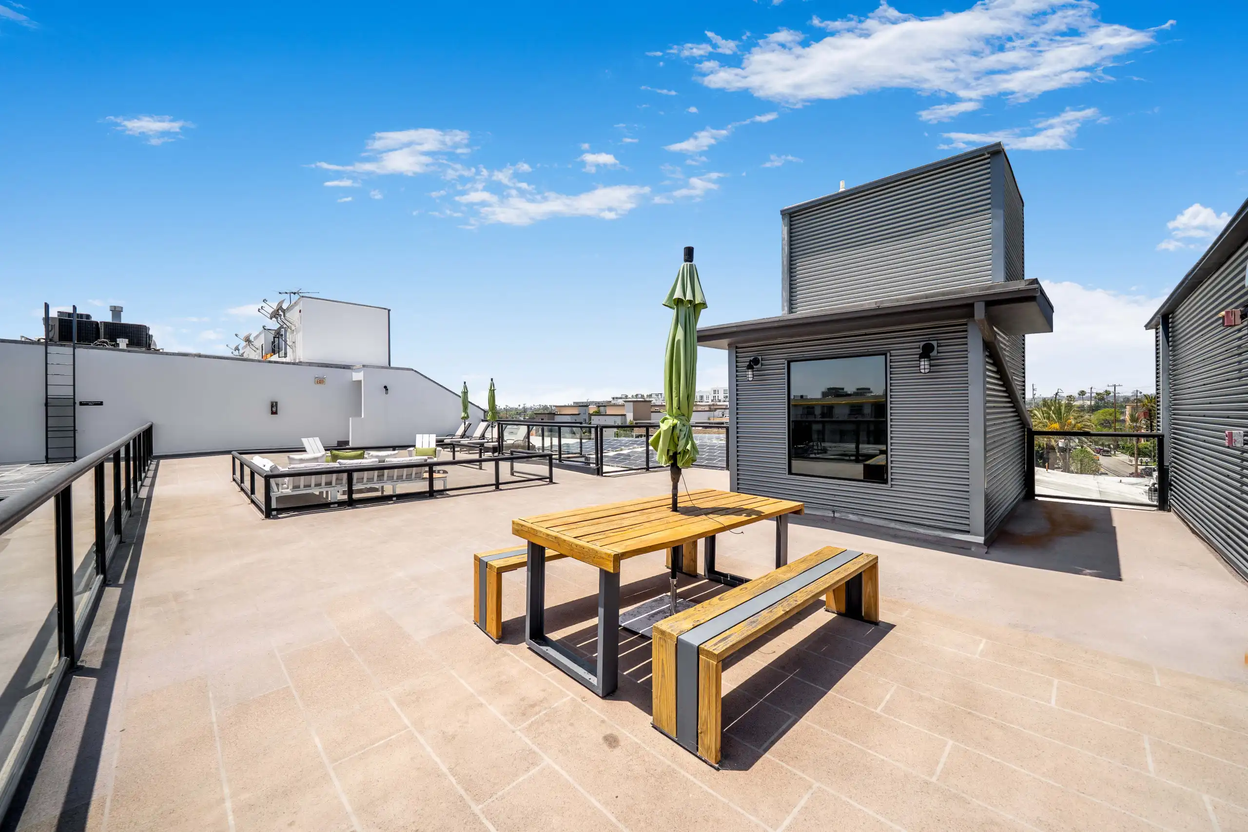 Rooftop deck with outdoor seating, wood picnic table, and metal railings in Marina Del Rey.