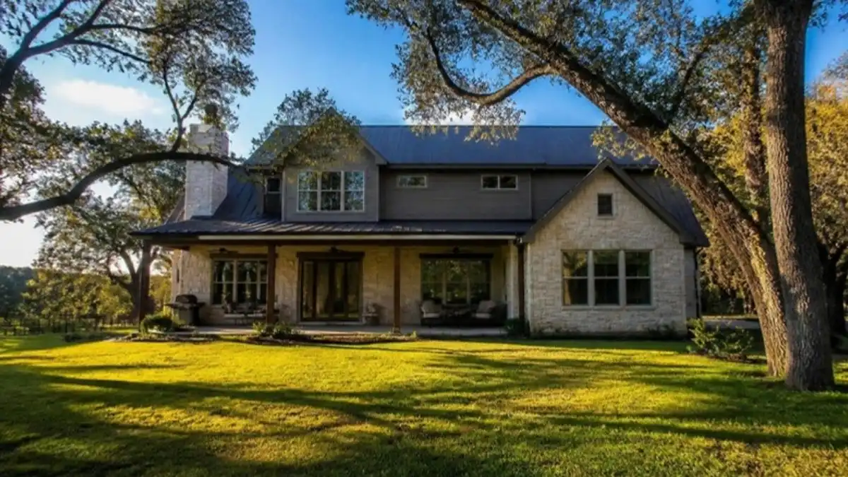 Two-story stone home with a big lawn and mature oak trees, for an Austin Texas home tour in Buda