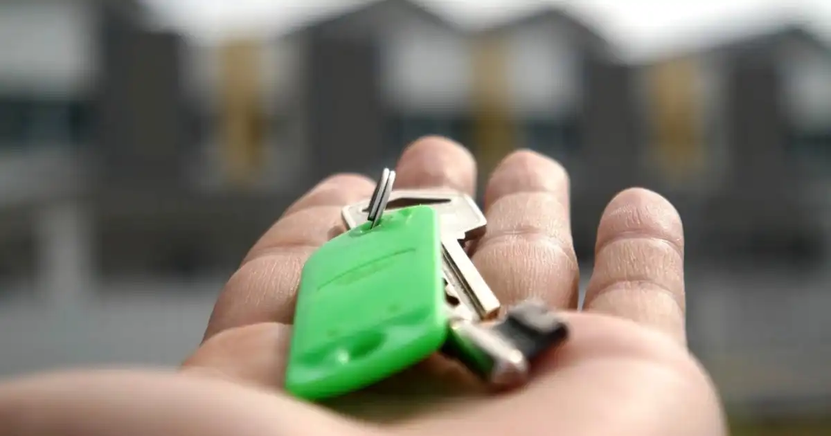 Hand holding a set of house keys with a green key tag