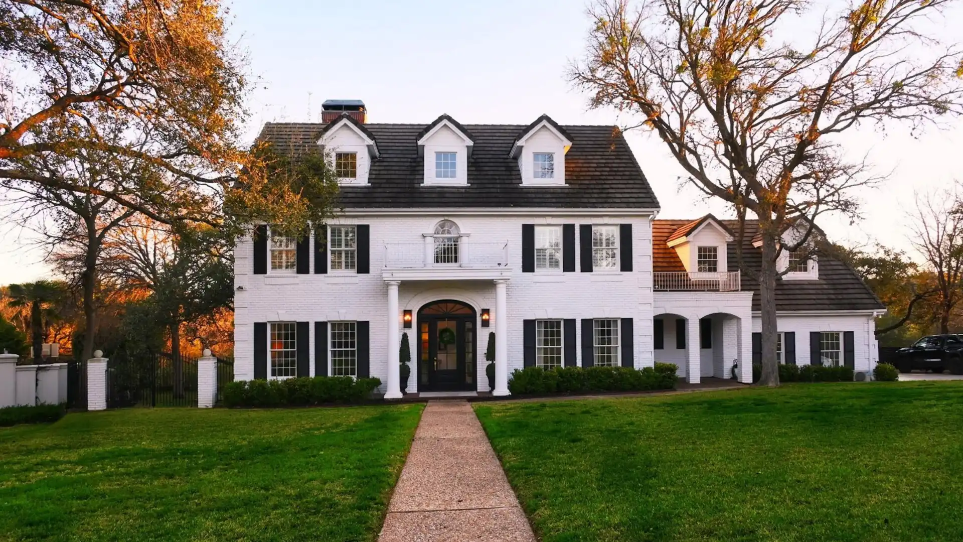 White brick two-story Colonial home with black shutters, arched entryway, and manicured front lawn in Nashville, Tennessee