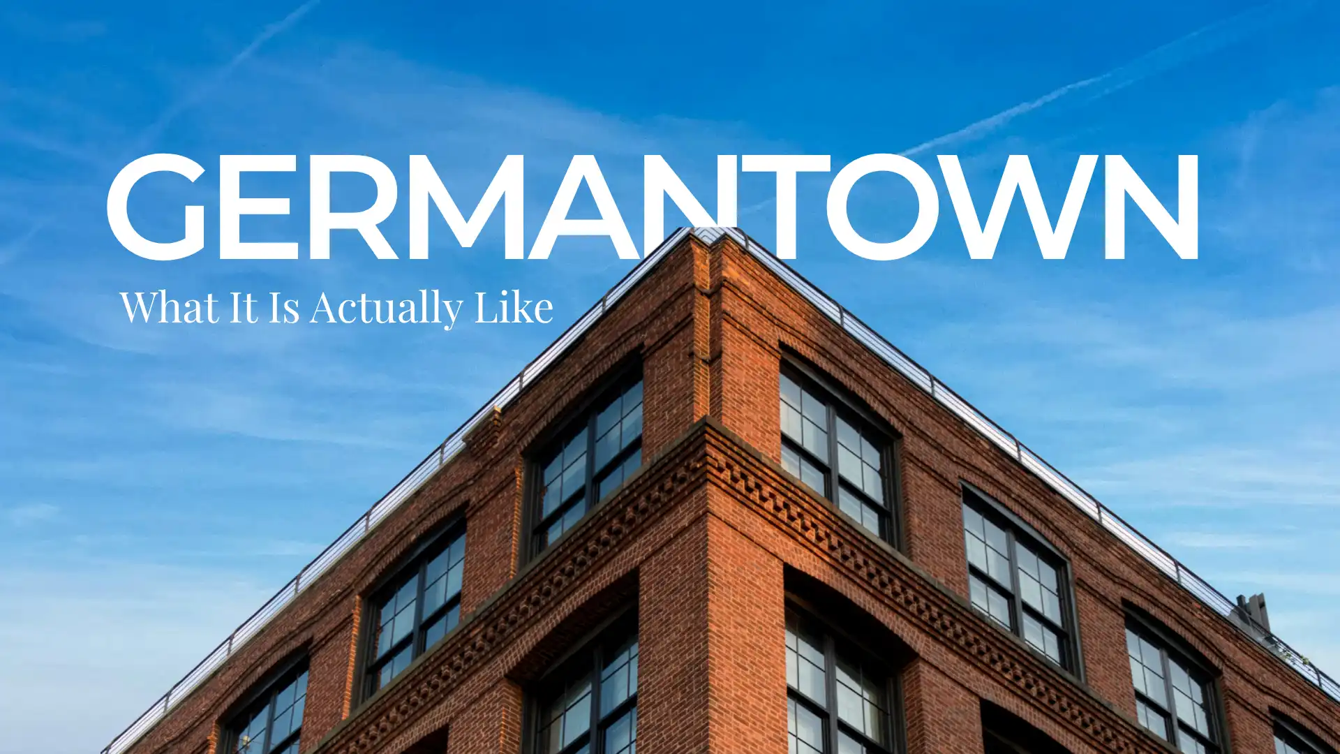 Corner of a historic red brick building with ornate detailing against a blue sky in Germantown Nashville with the neighborhood name and blog title overlaid
