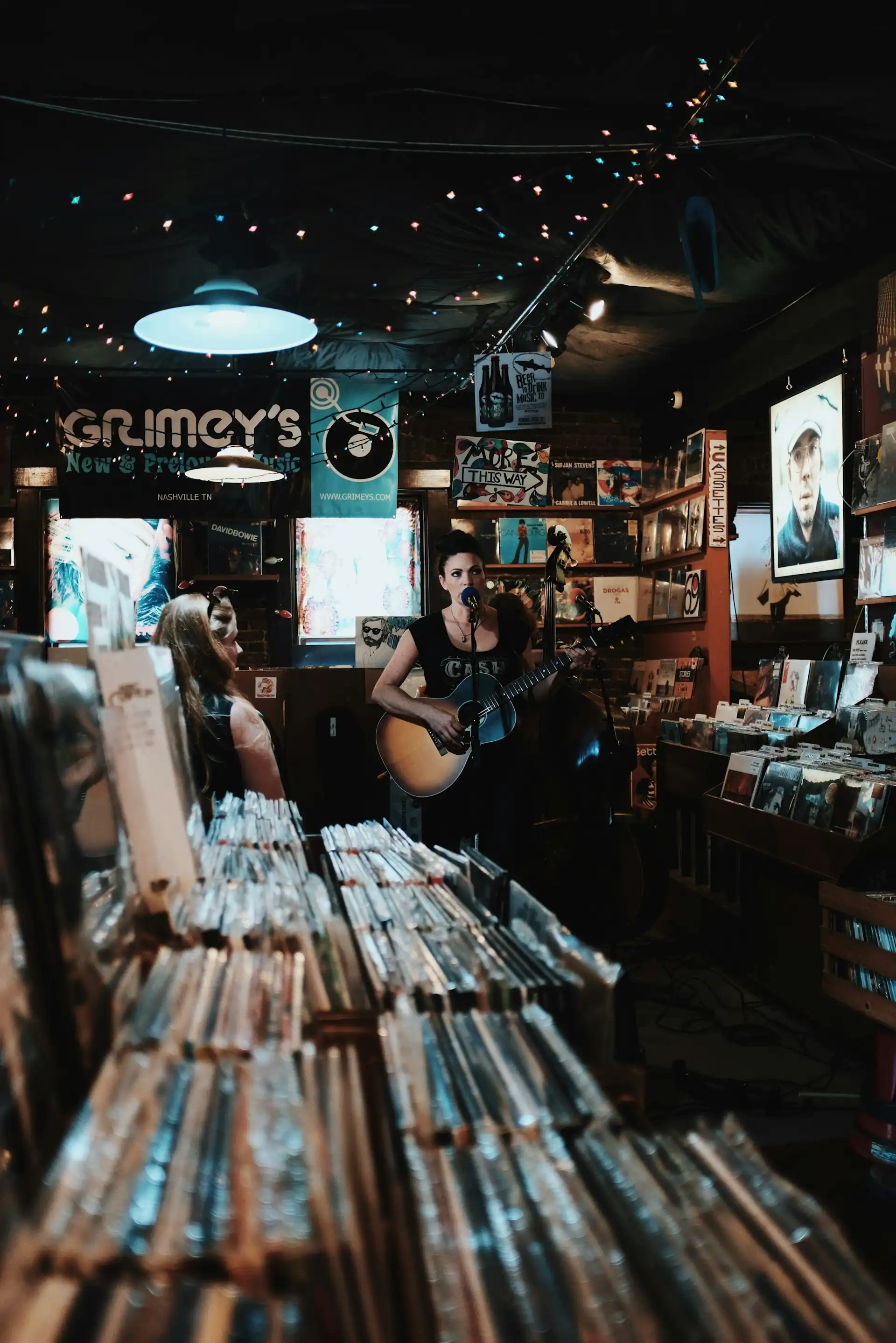 A singer with an acoustic guitar performing in an intimate Nashville record store