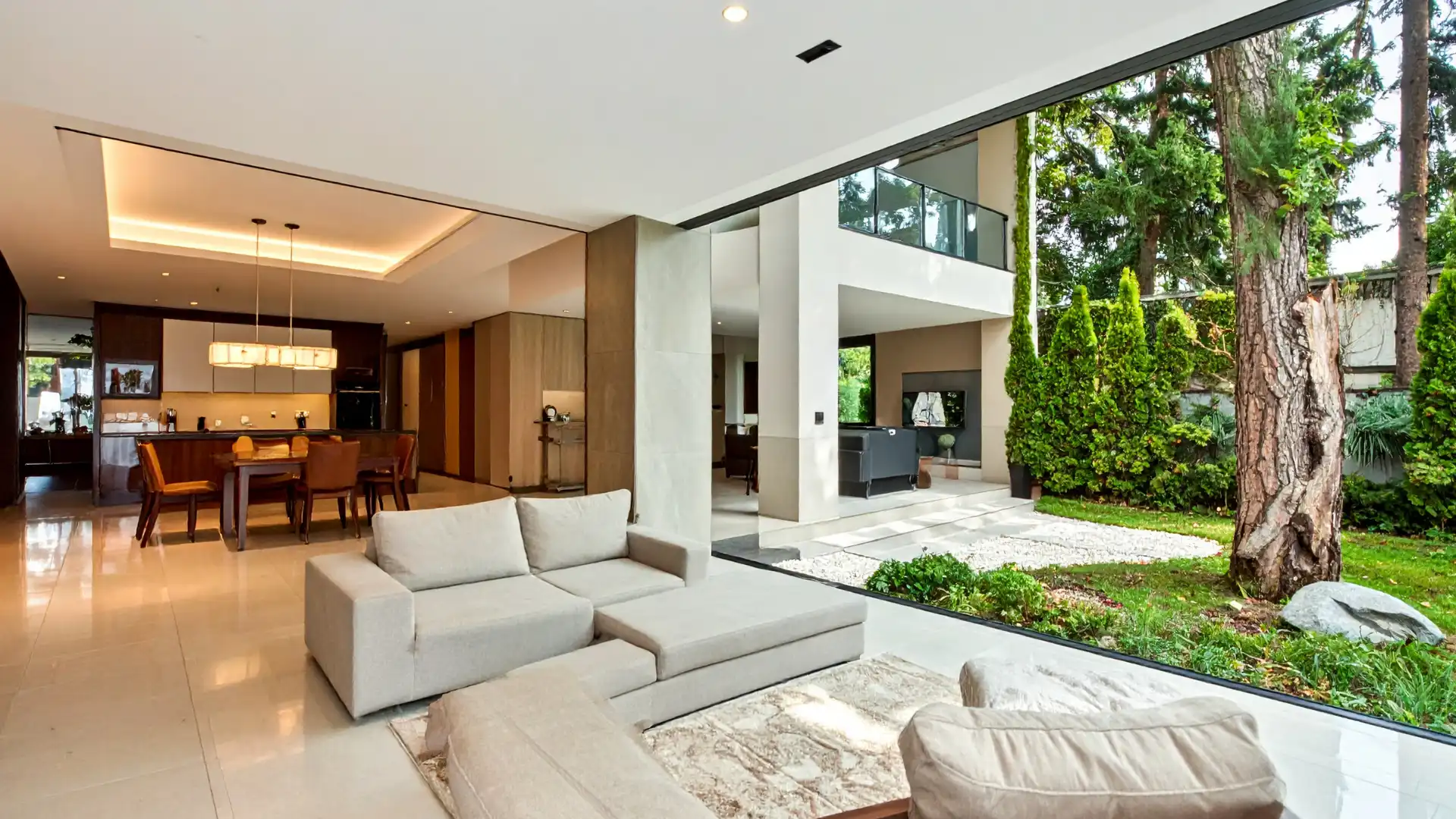 Bright modern luxury living room with floor-to-ceiling windows opening to a landscaped garden, representing a Nashville home for sale