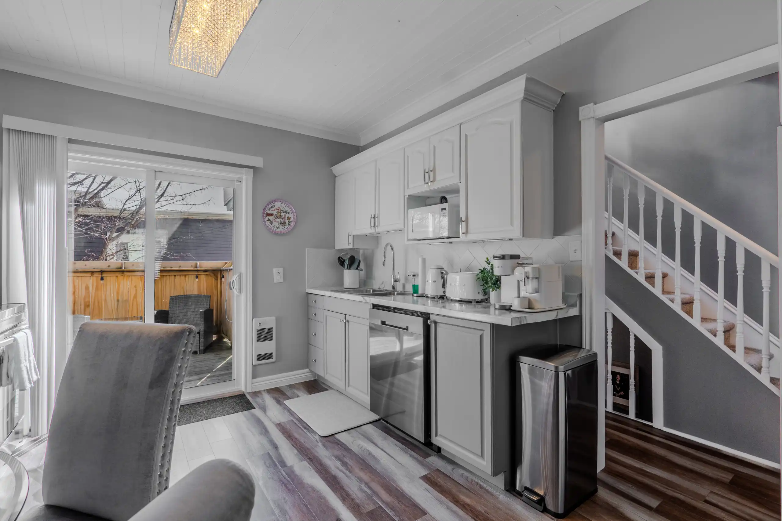 Bright kitchen with white cabinets, stairs and an adjoining dining area in a St. John’s home