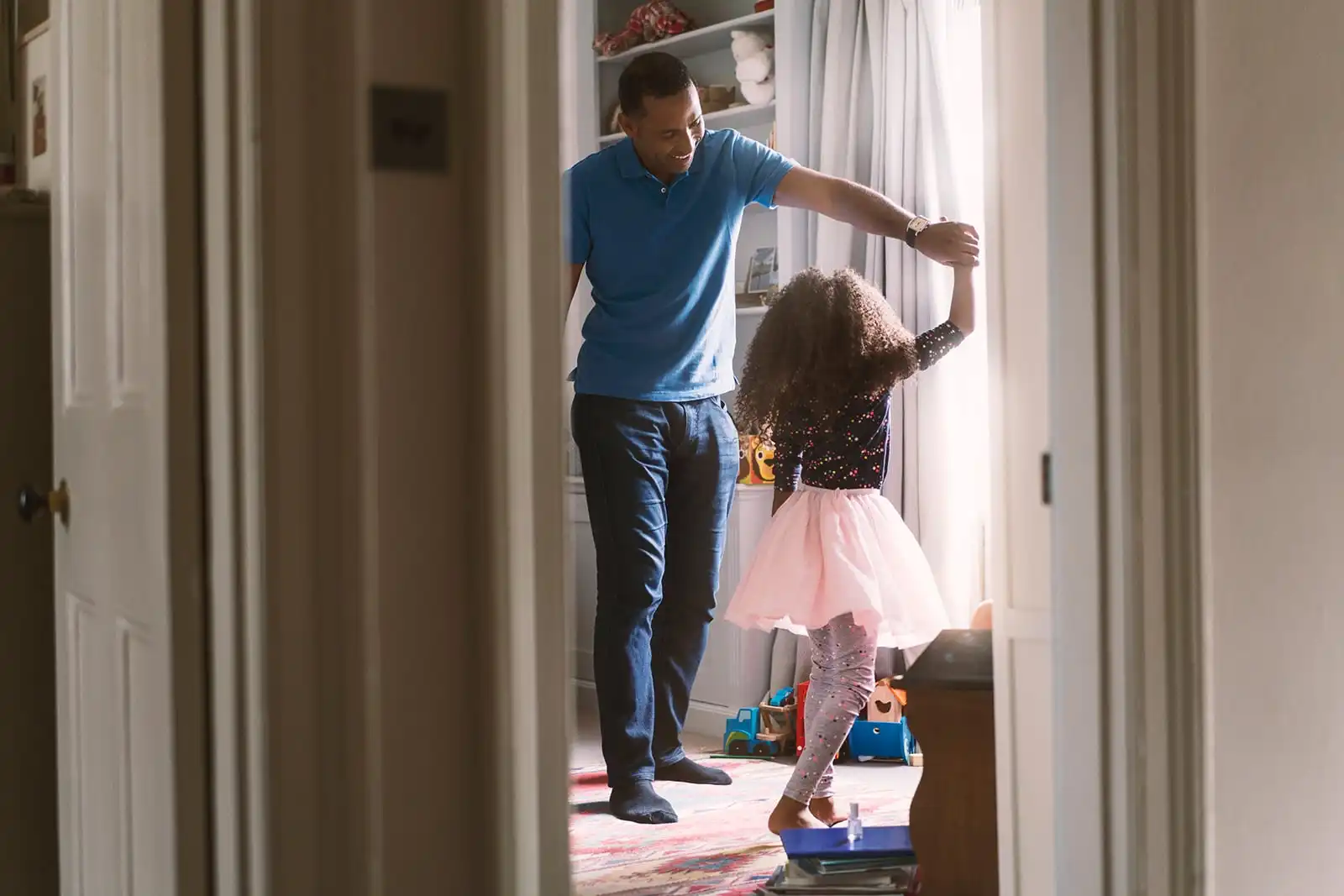 Adult and child dancing together in a bright room at home