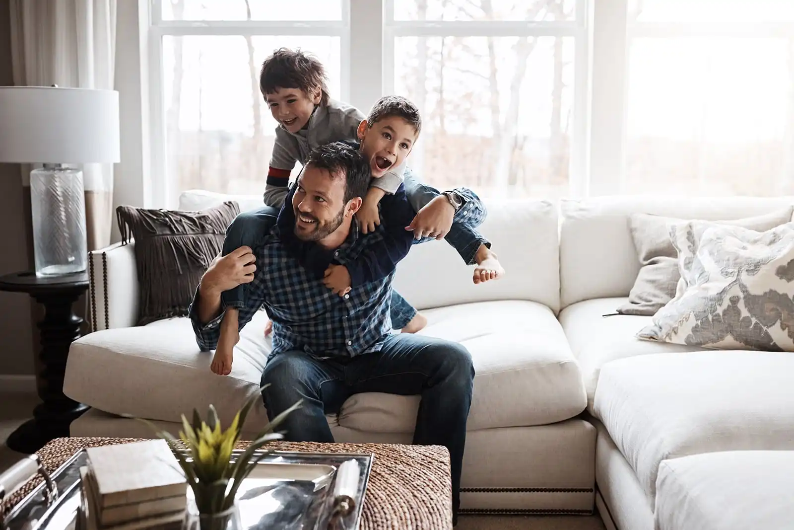 Adult and children playing beside a sofa in a bright living room